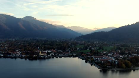 Aerial-hyperlapse-of-a-town-with-a-lake-between-mountains-in-Germany-during-sunset