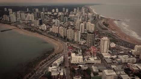Cinematic-aerial-shot-of-Punta-del-Este-City-with-sandy-beach-and-skyscraper-buildings-on-island-during-mystic-day---Uruguay,South-America