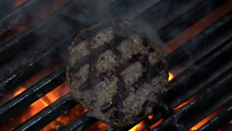 Grillen-Eines-Hamburger-Rindfleischpastetchens-über-Holzkohleflamme.---Nahansicht