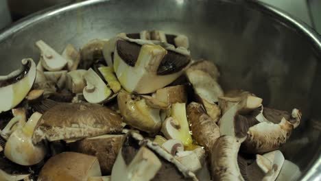 Pouring-olive-oil-ob-fresh-champignon-mushrooms-in-frying-pan,-close-up