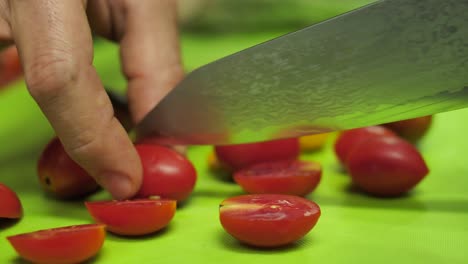 Chef-Cortando-Tomates-Cherry-En-Tablero-Verde-Con-Cuchillo-De-Acero-De-Damasco,-De-Cerca