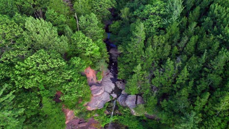 Toma-Aérea-De-La-Naturaleza-Siguiendo-Un-Pequeño-Río-Desde-Un-Acantilado