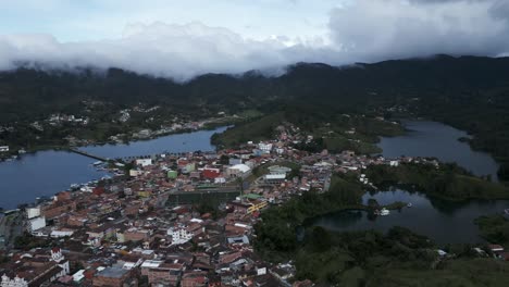Erstklassige-Luftdrohne-Fliegt-über-Guatape-Kolumbien-Stadt-Hügel-Lagune-Tropischen-Himmel