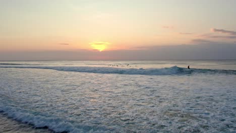 Vista-Aérea-Al-Atardecer-De-Un-Surfista-Atrapando-Grandes-Olas-En-El-Agua-Del-Océano-En-Uluwatu-Bali-Paradise-Indonesia