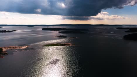 Dramatic-clouds-shadowing-islands-in-the-archipelago-of-Aland,-Finland---aerial-view