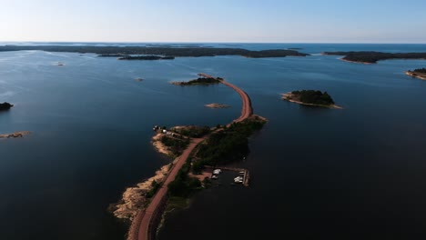 Aerial-view-overlooking-a-narrow-road,-linking-islands-in-Vardo,-Ahvenanmaa,-Finland---circling,-drone-shot