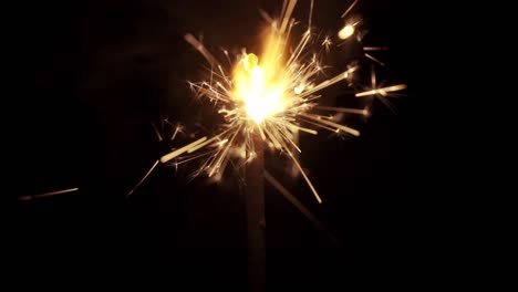 Macro-shot-of-a-sparkler-firework-as-it-burns-and-sparkles-in-dramatic-slow-motion,-isolated-in-front-of-a-black-background