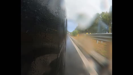 Punto-De-Vista-Desde-El-Lado-Derecho-Del-Automóvil-Cerca-De-La-Rueda-Derecha-Conduciendo-Por-La-Autopista-Durante-Un-Día-Lluvioso-En-Sydney-Australia-Punto-De-Vista-Del-Automóvil-Mientras-Conduce-Pasando-El-Letrero-De-80-Velocidades-Y-La-Barrera-De-Metal-En-Medio-De-La-Carretera