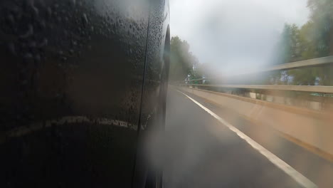 Black-car-moving-over-bridge-giving-view-of-other-lane-moving-in-opposite-direction-and-trees-along-side-the-road