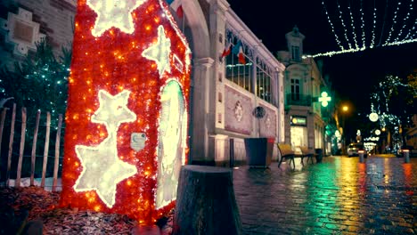 A-wide-crane-movement-shot-of-a-beautiful-Christmas-decorations-in-a-French-street-with-a-big-red-santa-mailbox-in-the-field