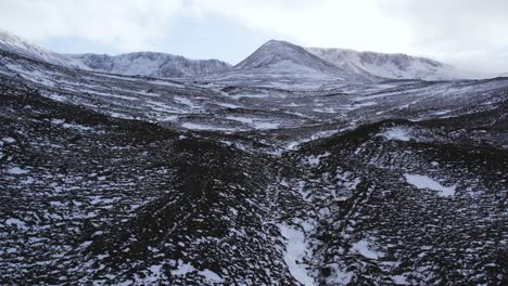 Static-aerial-drone-footage-of-Fiacaill-Coire-an-t-Sneachda-in-the-Cairngorms-National-Park-in-Scotland-in-winter-with-an-icy-river-flowing-down-a-frozen-glen-with-snow-covered-heather-moorland