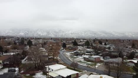 Eine-Luftdrohne-Schoss-Rückwärts-über-Ein-Wohngebiet,-In-Der-Ferne-Ein-Spektakulärer-Blick-Auf-Die-Schneebedeckten-Wasatch-Berge-An-Einem-Kalten,-Düsteren-Wintertag,-Layton,-Utah