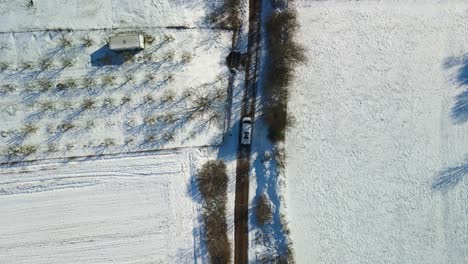 Aerial-view-of-a-van-driving-on-a-narrow-path-in-the-middle-of-the-fields-on-a-sunny-winter-day,-Dalmatia,-Croatia