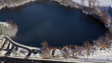 An-aerial-view-over-a-pond-on-a-sunny-day-after-a-snow-fall
