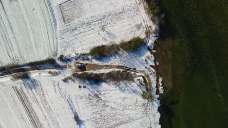 Aerial-view-of-a-van-stoping-at-a-dead-end-in-a-rural-landscape-covered-with-snow-next-to-Cetina-river-on-a-beautiful-winter-day,-Dalmatian,-Croatia