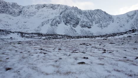 Aerial-drone-footage-close-to-the-ground,-approaching-the-headwall-of-Coire-an-t-Sneachda-in-the-Cairngorm-mountains-of-Scotland-in-snow,-ice-and-full-winter-mountaineering-conditions