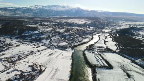 Aerial-panoramic-view-of-Celina-river-with-snowy-landscape-and-the-sunlight-reflecting-in-the-water,-Dalmatian,-Croatia