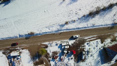 Aerial-view-of-a-van-driving-on-a-rural-road-with-snowy-landscape-on-a-sunny-winter-day,-Dalmatia,-Croatia