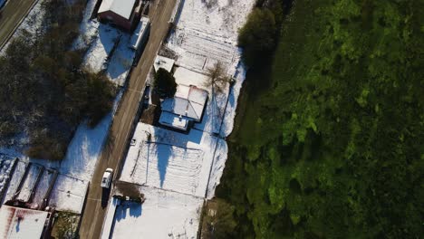 Aerial-view-of-a-van-driving-in-a-village-covered-with-snow-next-to-Cetina-river-on-a-beautiful-winter-day,-Dalmatian,-Croatia