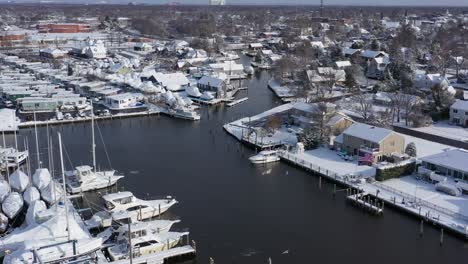 A-drone-view-over-a-marina-in-Bay-Shore,-NY-in-the-morning-after-a-recent-snowfall