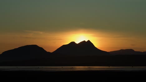 Zoom-in-shot-showing-silhouette-of-Icelandic-mountain-range-and-golden-sunset-in-backdrop