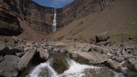 Hengifoss-Waterfall-Flowing-Into-Rocky-Stream-At-Summer-In-Hengifossa-in-Fljotsdalshreppur,-East-Iceland