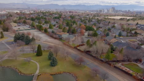 Slow-pull-back-from-neighborhood-in-Reno,-Nevada-and-over-a-park-with-a-pond-in-the-foreground