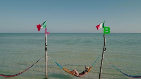 Female-tourist-with-straw-hat-laying-in-Holbox-hammocks,-sunny-day
