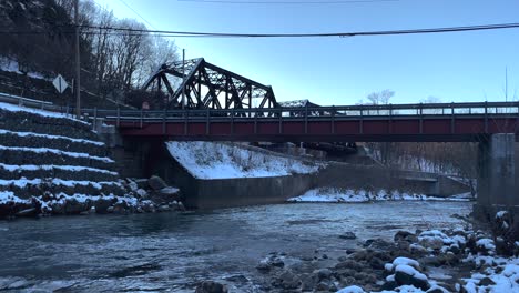 Railroad-bridge-with-stream-in-winter-snow