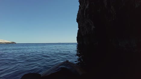 Kajakfahrer-Kommt-Aus-Einer-Natürlichen-Meereshöhle-Und-Blickt-Durch-Die-Öffnung-Auf-Den-Horizont,-Gegenüber-Der-Insel,-Adria,-Kroatien