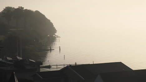 Houses-with-privat-boot-docks-jetty-at-calm-bay-in-the-morning-foggy-early-in-scandinavia