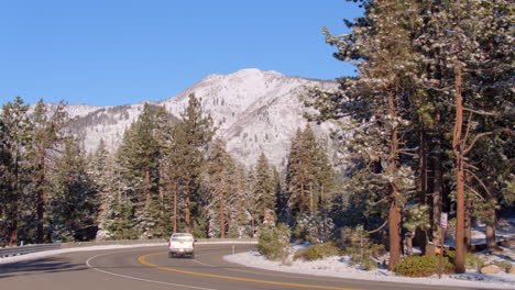 A-truck-drives-away-on-a-winding-road-in-Lake-Tahoe,-Nevada-with-a-mountain-in-the-background