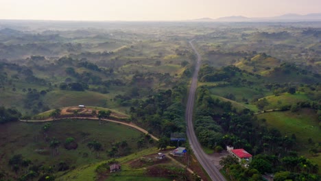 Slow-aerial-flight-over-rural-road-surrounded-by-lush-mystical-landscape-with-hills-and-fog-during-sunset-time---Las-Terrenas,Dominican-Republic