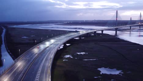 Aerial-view-Mersey-gateway-illuminated-curved-freeway-bridge-overpass-lanes-early-morning-sunrise-pull-away