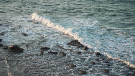 Slow-Motion-Beach-Waves-Crashing-On-Dark-Rocky-Shore,-4K