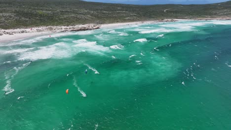 Aerial-view-of-group-practicing-windsurfing-at-Platboom-beach,-South-Africa