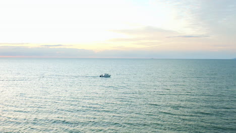 Fischerboot,-Das-Bei-Sonnenaufgang-Entlang-Der-Meeresoberfläche-Rast,-Mit-Buntem-Himmel,-Luft-4k-Drohne
