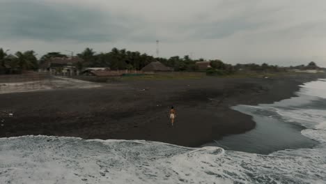 Mädchen,-Das-Am-Strand-Spazieren-Geht,-Während-Meereswellen-An-Der-Sandigen-Küste-In-El-Paredon,-Guatemala,-Angespült-Werden