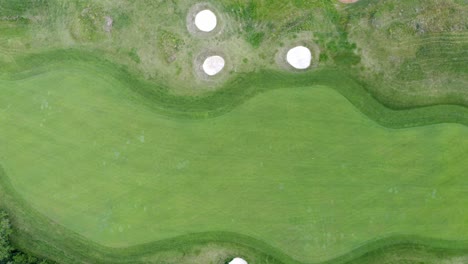 Overhead-flyover-of-green-golf-course-with-sand-bunkers