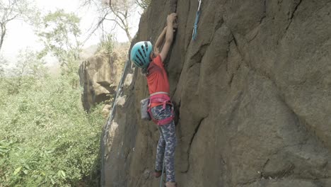 Static-shot-of-an-8-year-Indian-girl-rock-climbing-in-the-outdoors