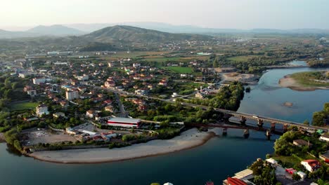Antena-De-La-Ciudad-De-Shkoder-En-Albania-Con-Un-Río,-Un-Puente-Y-Montañas