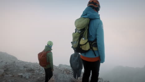 Wanderer-Mit-Helm-Und-Rucksack-Versuchen-Am-Frühen-Morgen-Durch-Nebel-Und-Wolken-Ins-Tal-Zu-Blicken
