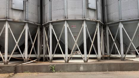 Panning-shot-of-multiple-large-metal-feeding-silos