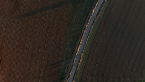 Top-Down-View-Over-Dusty-Narrow-Road-Between-Empty-Countryside-Fields