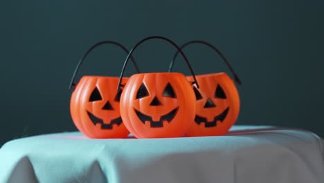 Mini-Halloween-Pumpkins-On-White-Cloth-with-Colored-Lights-in-Background