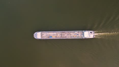 Aerial-drone-top-shot-flyover-an-oil-and-gas-blue-cargo-inland-vessel-ship-on-the-river-Rhein-in-Cologne,-Germany---vertical-bird-view-over-tanker-on-green-river---summer-2022