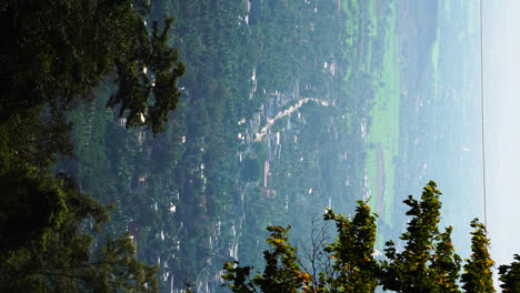 Vista-Alta-De-La-Ciudad-De-Thôn-Gòn-En-Vietnam-Con-Ramas-De-árboles-Y-Hojas-En-Primer-Plano