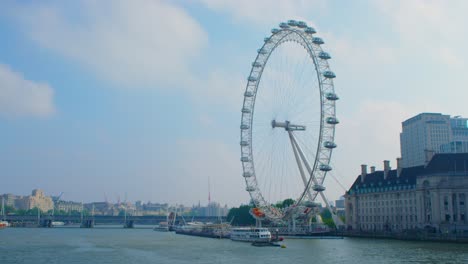 Slow-motion-pan-of-the-closed-London-Eye-not-moving-over-the-Thames-River-reflecting-the-summer-sun,-during-the-Covid-19-lockdown-pandemic-2020