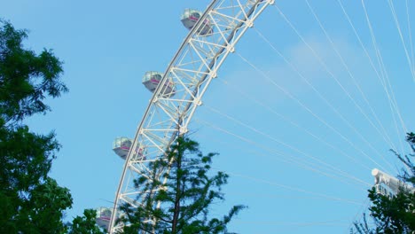 Lockdown-in-London,-static-shot-of-empty-London-Eye-capsules-not-turning-or-moving-with-trees-being-blown-in-a-summer-breeze,-during-the-COVID-19-pandemic-2020