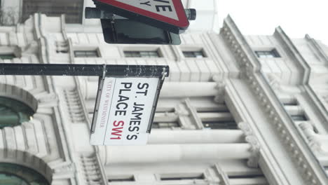 Vertical-view-of-a-St-James's-Street-SW1-street-signboard-in-central-London,-UK-with-the-view-of-a-white-building-in-the-background